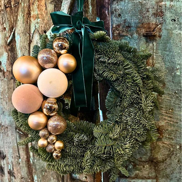Ghirlanda natalizia verde con palline oro e fiocco in velluto verde scuro.
