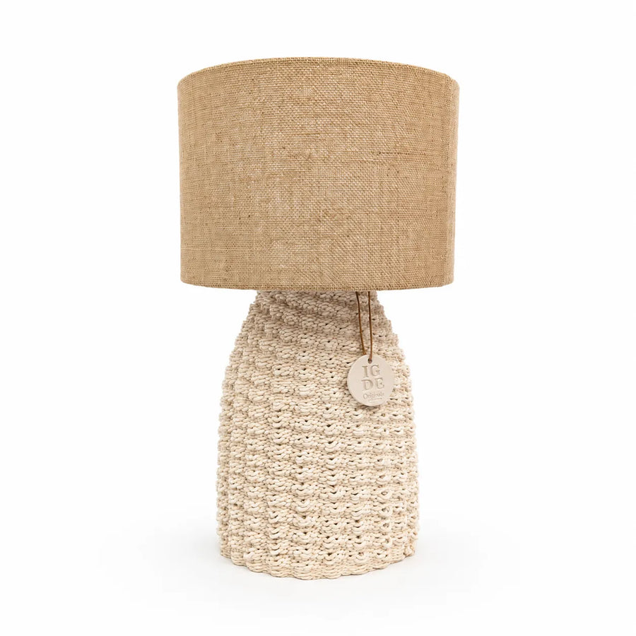 Lampada artigianale Fira accesa su comodino in legno con illuminazione soffusa e atmosfera accogliente in camera da letto.