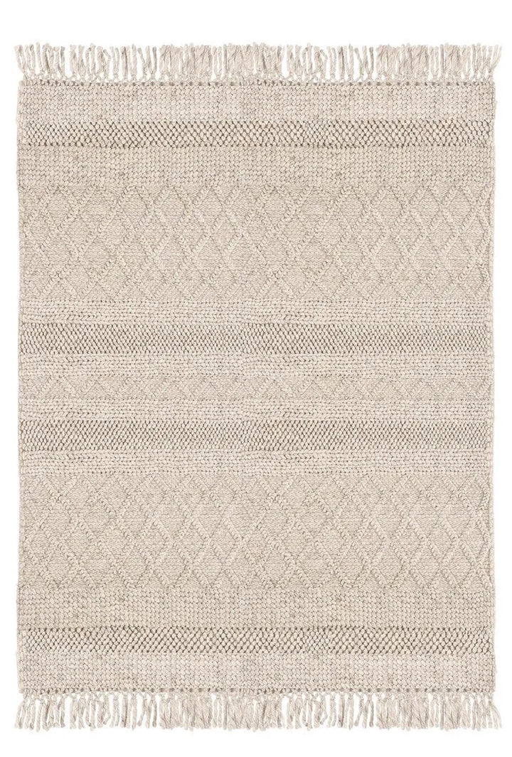 Vista dall’alto di un tappeto intrecciato beige con motivi a rombi e frange, ideale per arredamenti naturali e minimalisti