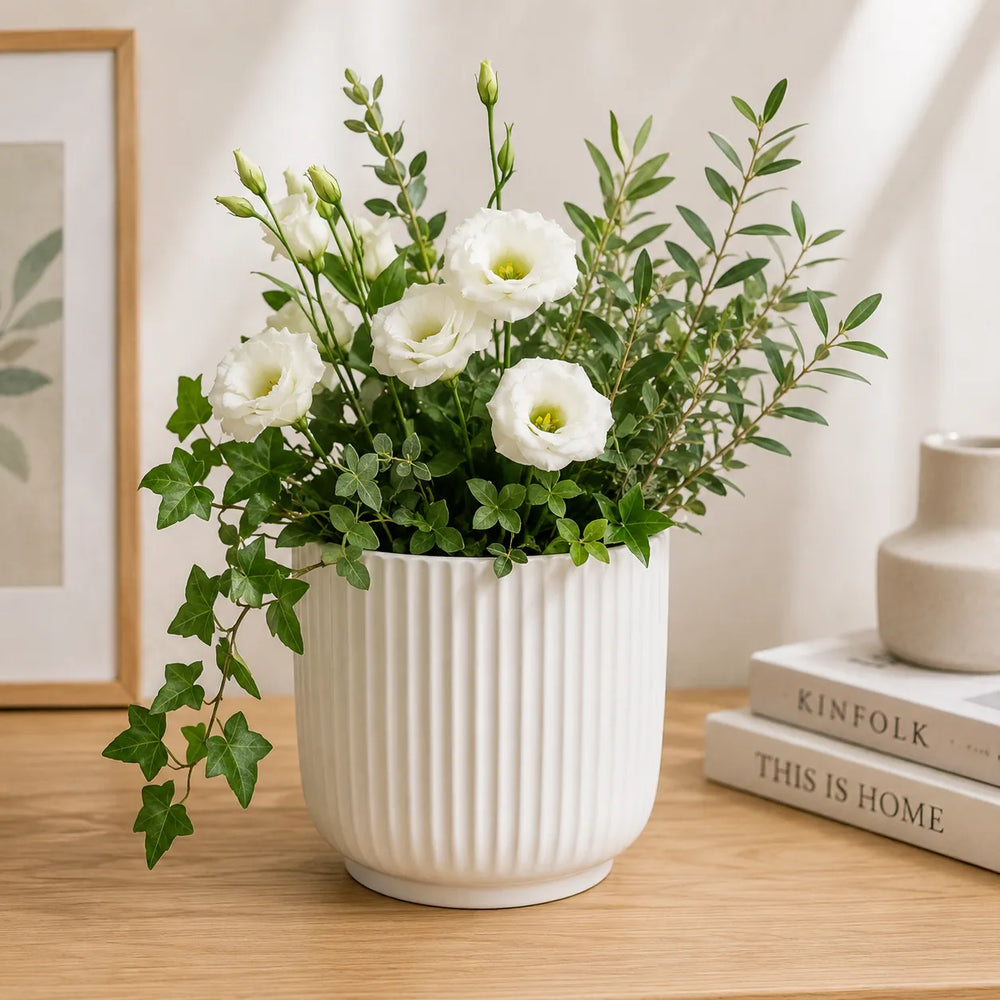 Vaso Pitti bianco rigato con composizione di fiori bianchi e fogliame verde, ideale come centrotavola o decorazione per ambienti eleganti e contemporanei.