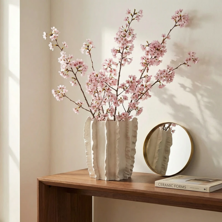 Vaso artigianale con rami di fiori rosa su mobile in legno stile minimal elegante